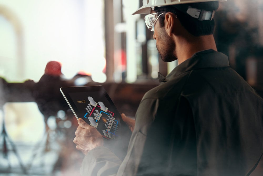 Man in factory with tablet managing Industrial IoT in factory.
