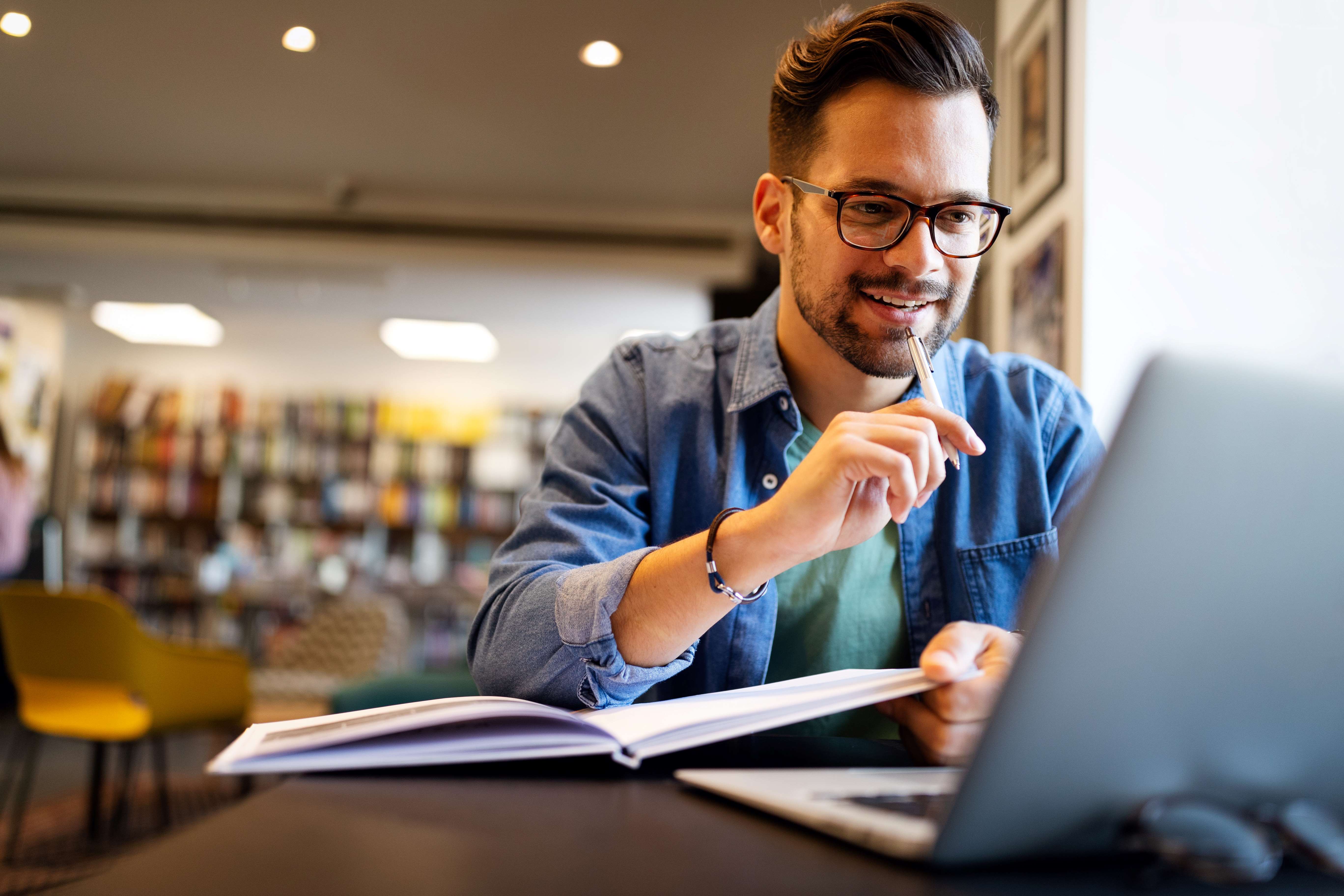 man studying 5G on laptop with book