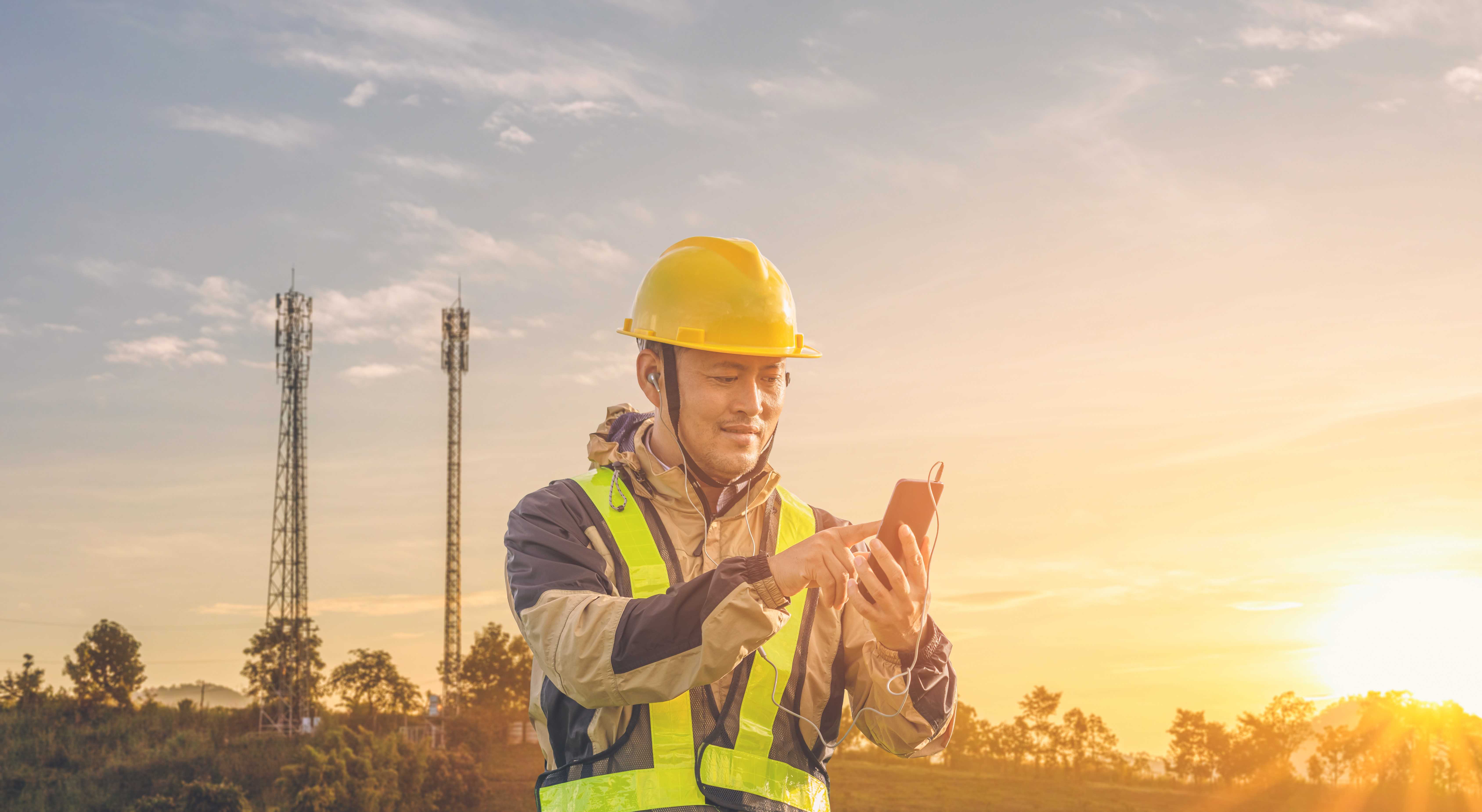 Engineer testing 5G antenna tuners with cell towers in the background