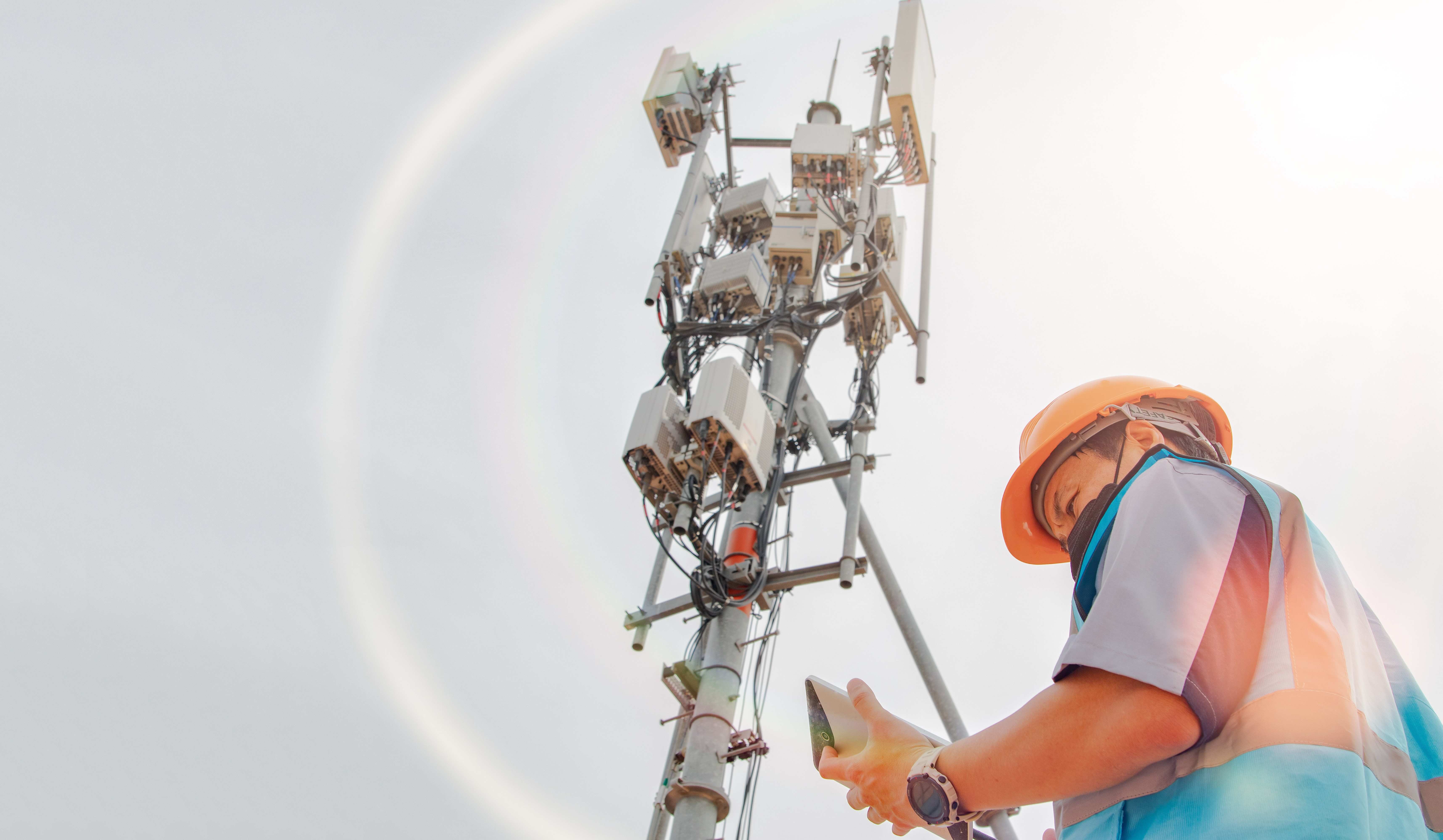 man near cell tower performing 5G log analysis