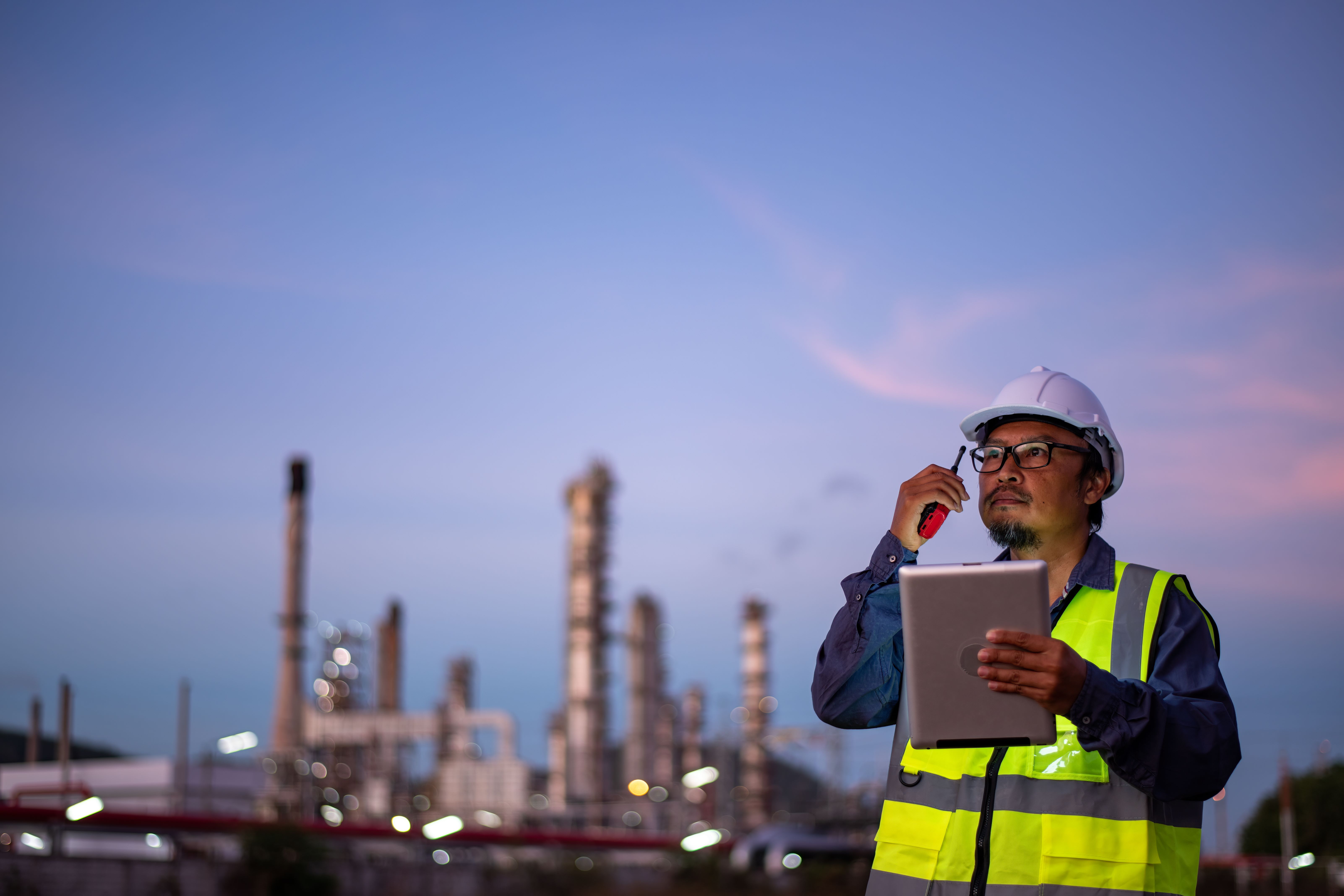 man on tablet performing 5G log analysis with factory in background